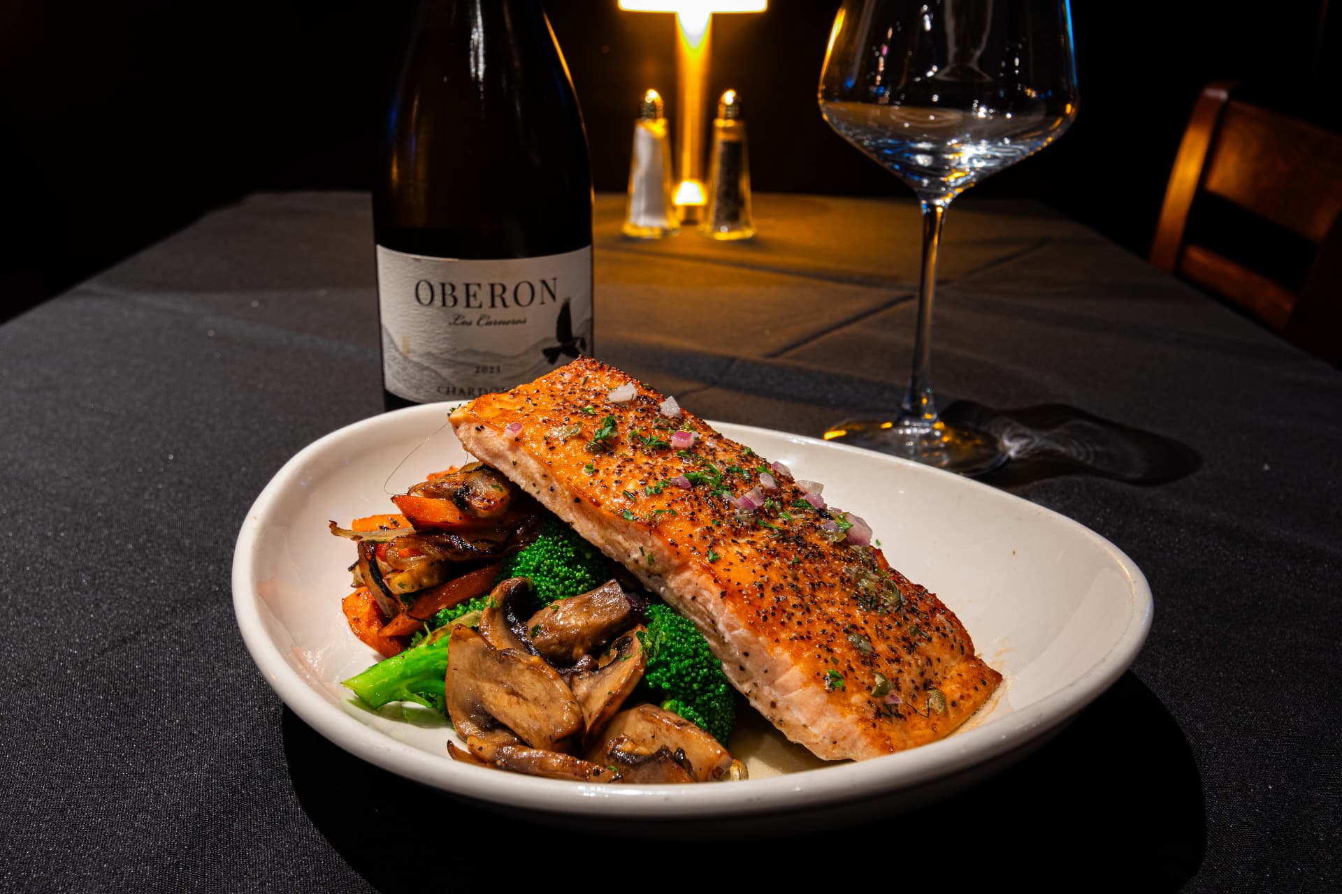 Pan-seared salmon with seasonal vegetables and a glass of white wine